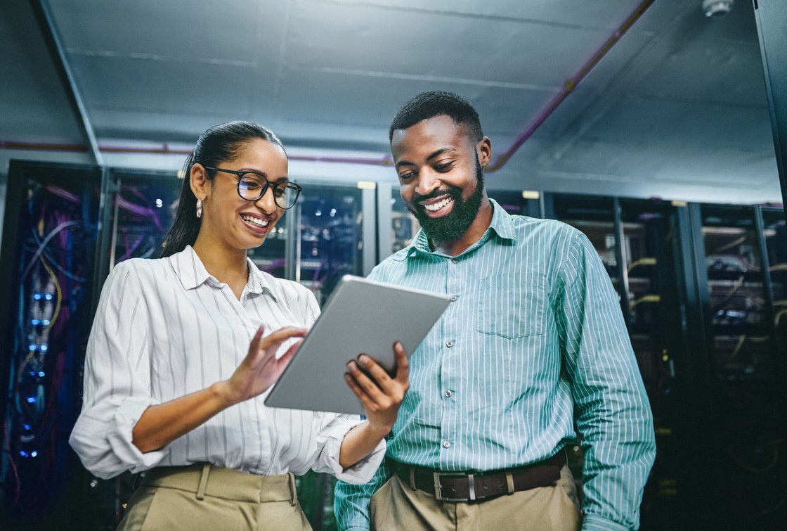 two coworker looking at tablet in front of server tech