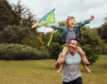 father and son flying kite at a park