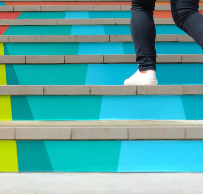 shoes of someone running up colorful stairs
