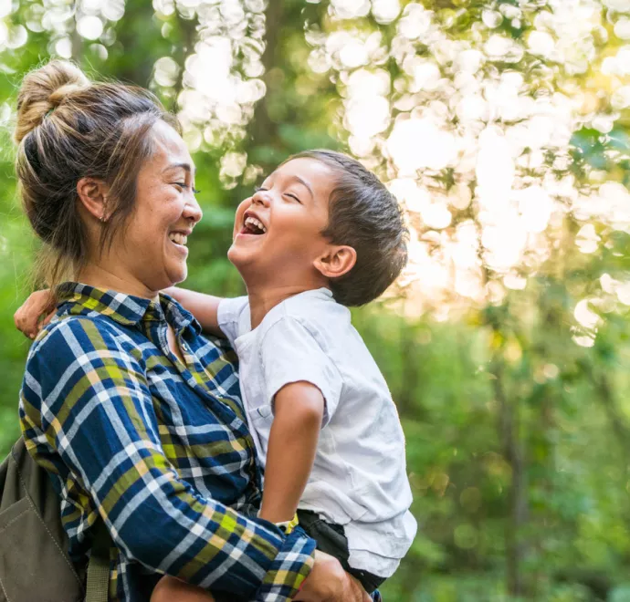 mom and child laughing in the trees